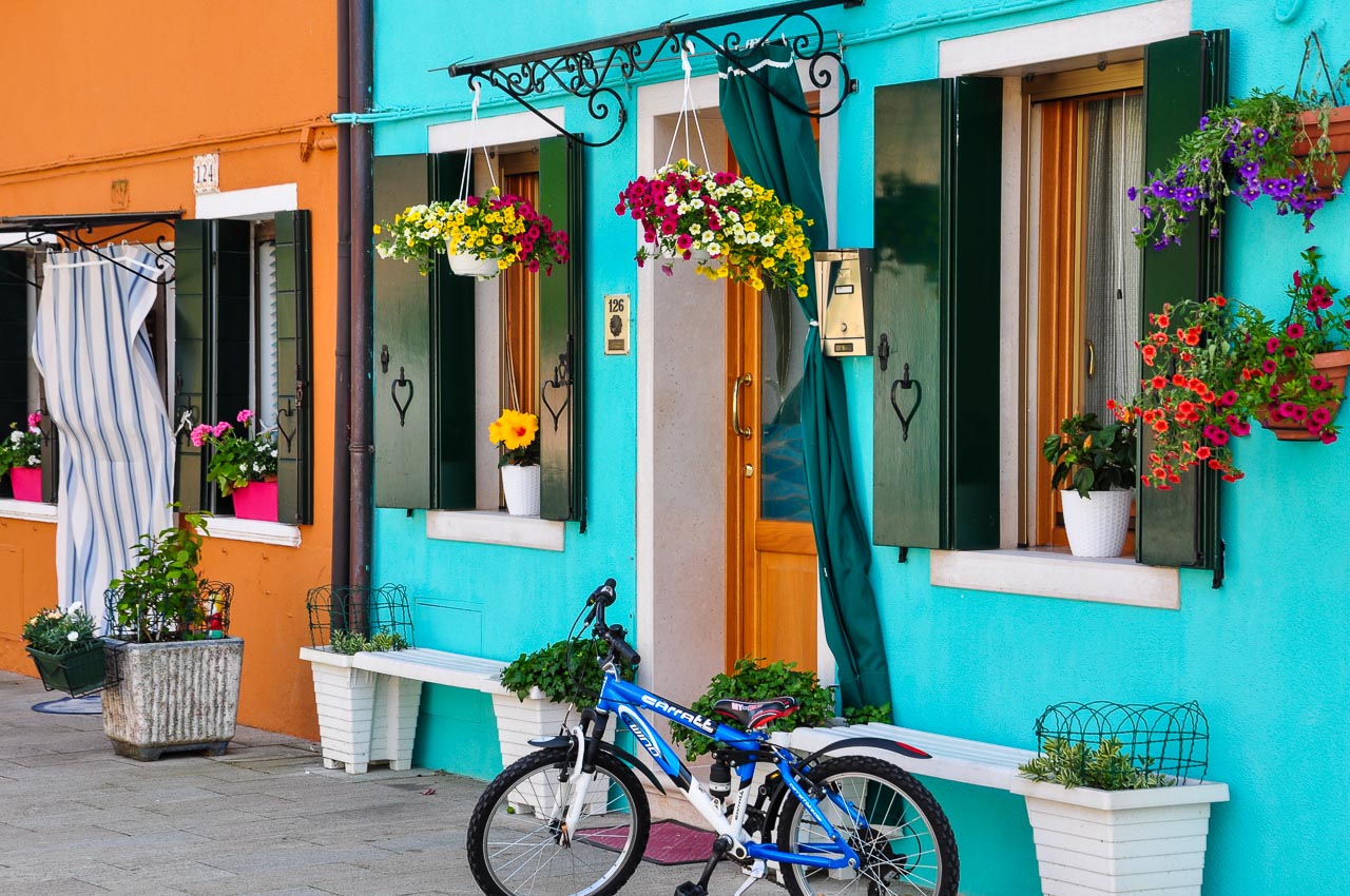 Coloured house with hanging baskets of flowers and bicycle in front