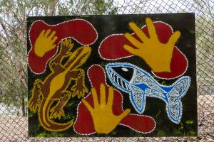 a painting of a fish, a goanna, and hands prints