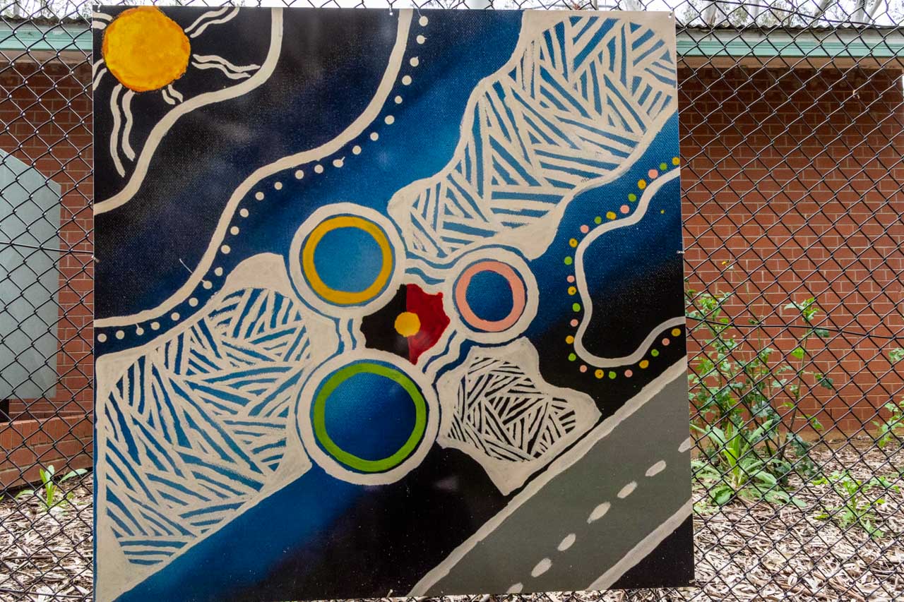 A painting of a road, the sun, and the Aboriginal flag