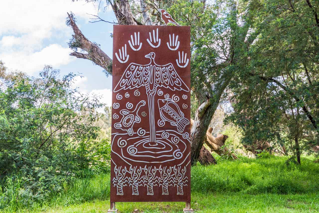 A metal panel with birds, fish, yabbies, turtle and handprints carved on it