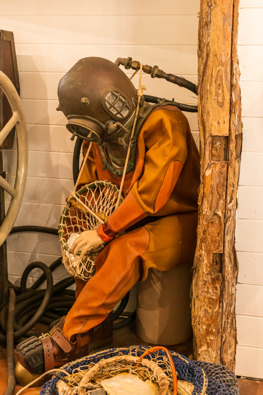 A mannequin dressed in an old pearl diver suit, including the weights the pearl divers carried on their feet, chest, back, belt and diving helmet