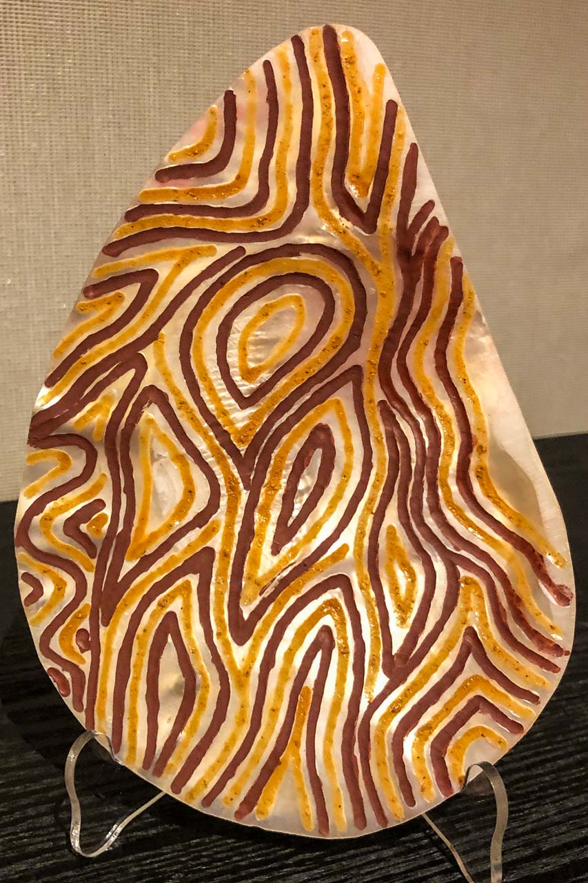 A carved oyster shell with brown and yellow lines