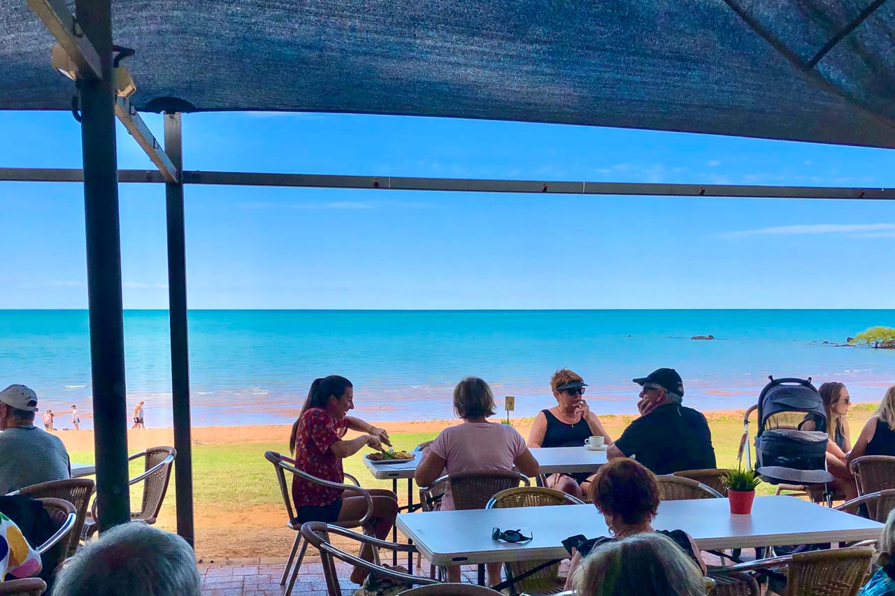 People eating at outdoor tables with a view of the beach