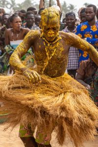 A male voodoo devotee dressed in a straw skirt and twirling