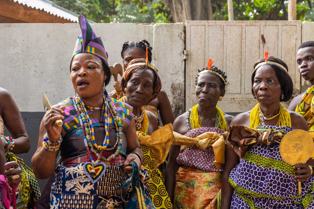 a group of women dressed in multi-coloured clothing and each wearing many bead necklaces.