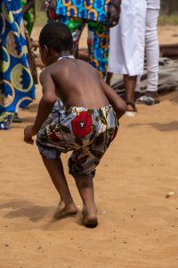 Young boy dancing in colourful shorts on sand