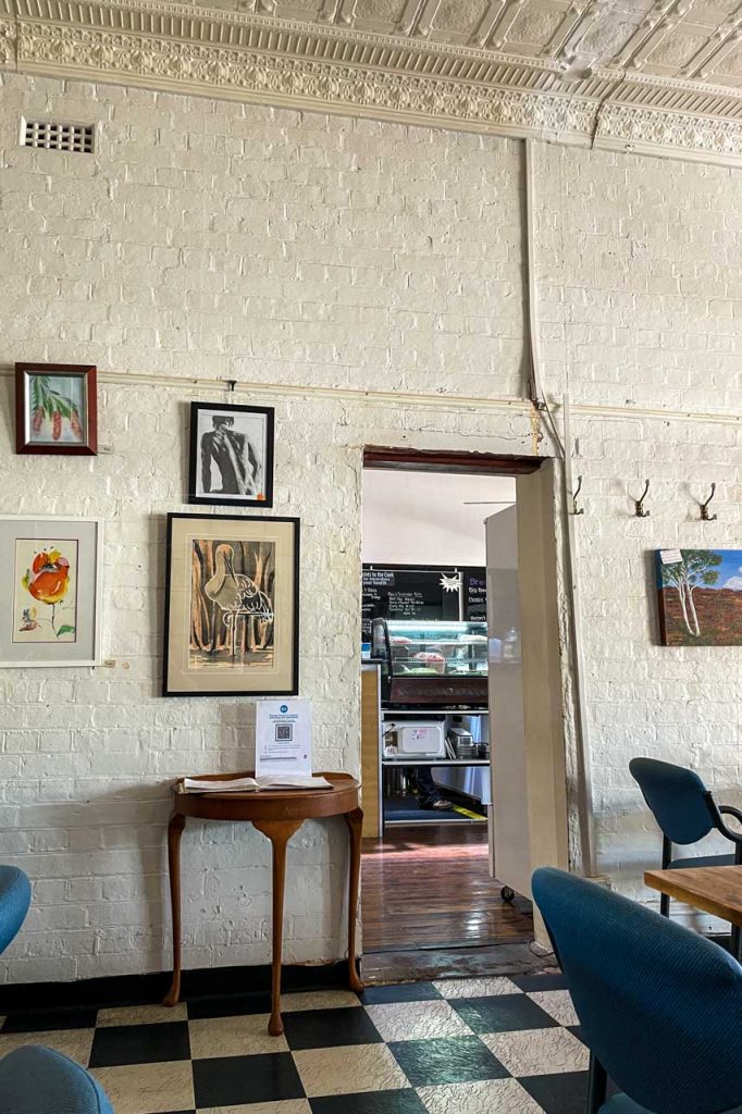 A picture of inside a cafe with table and chairs and pictures on the walls