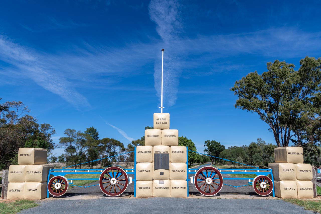 A picture of a memorial with three pillars of replica bales of wool