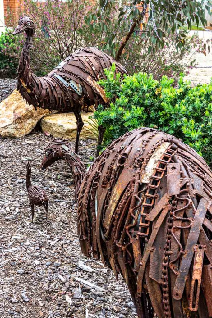 A rusty metal sculpture of two adult emus and an emu chick