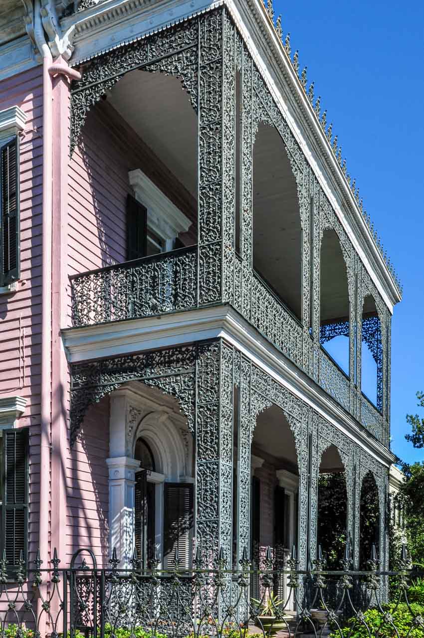 A two-story, pink weatherboard house with cast-iron balconies.