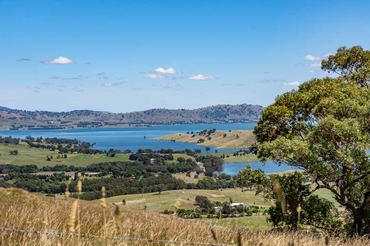 A view of a lake, hills and pasture land taken from a lookout.