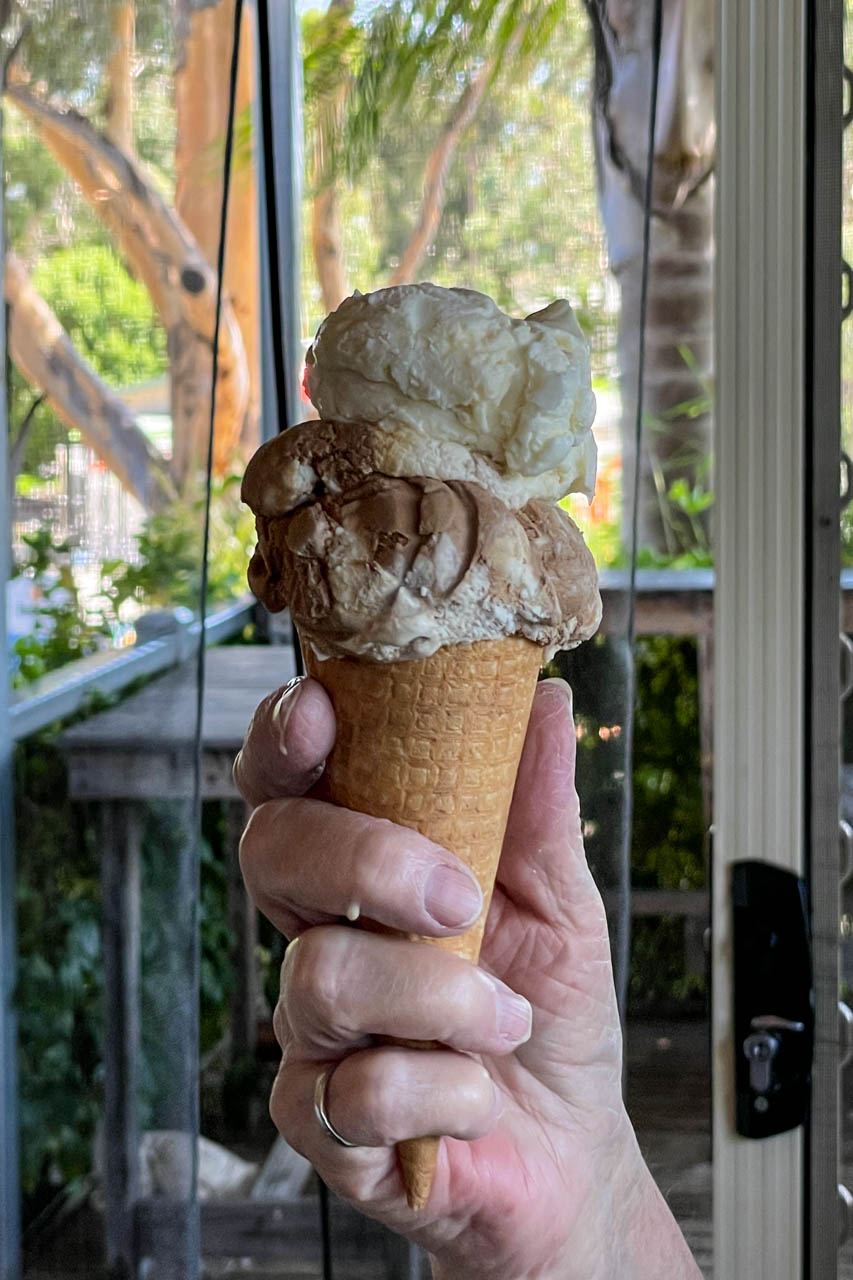 Two flavours of ice cream in a waffle cone in a person's hand