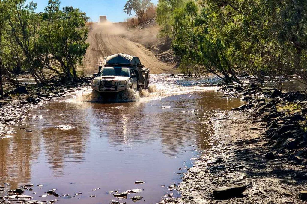 A four-wheel-drive vehicle crossing a flooded river.