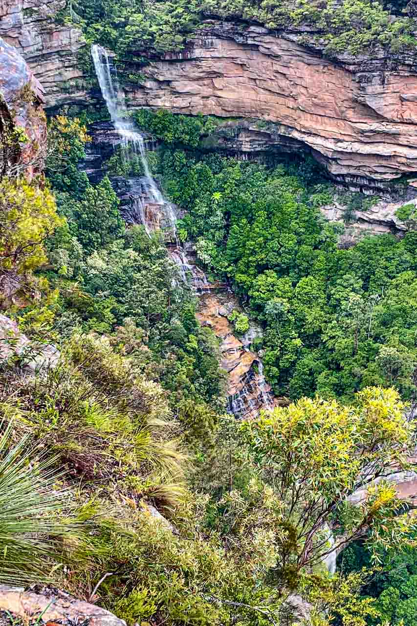 Photo of a multi-tiered waterfall plunging down a cliff and surrounded by bushland.