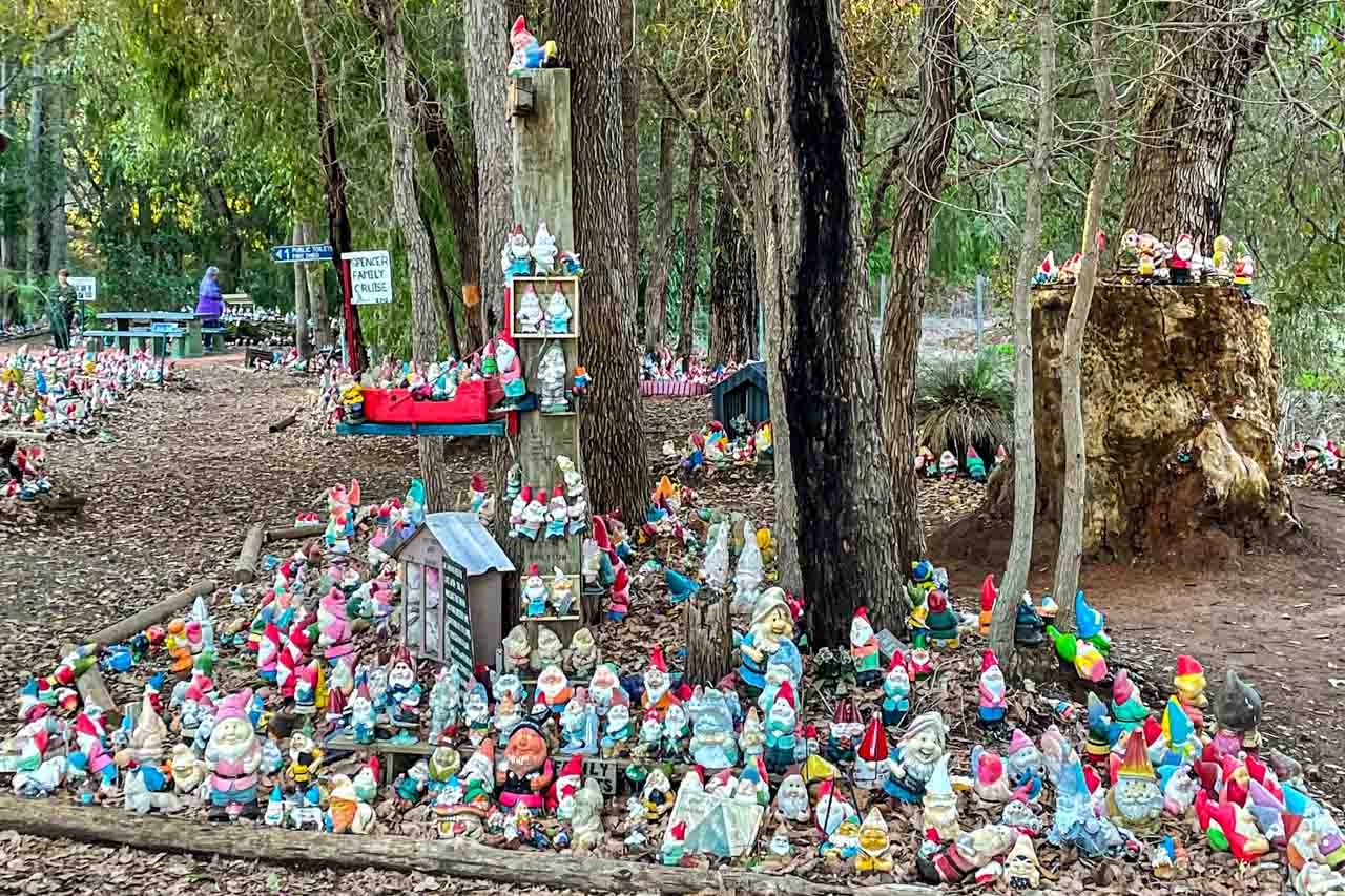 A photo of hundreds of garden gnomes on the ground and in the trees