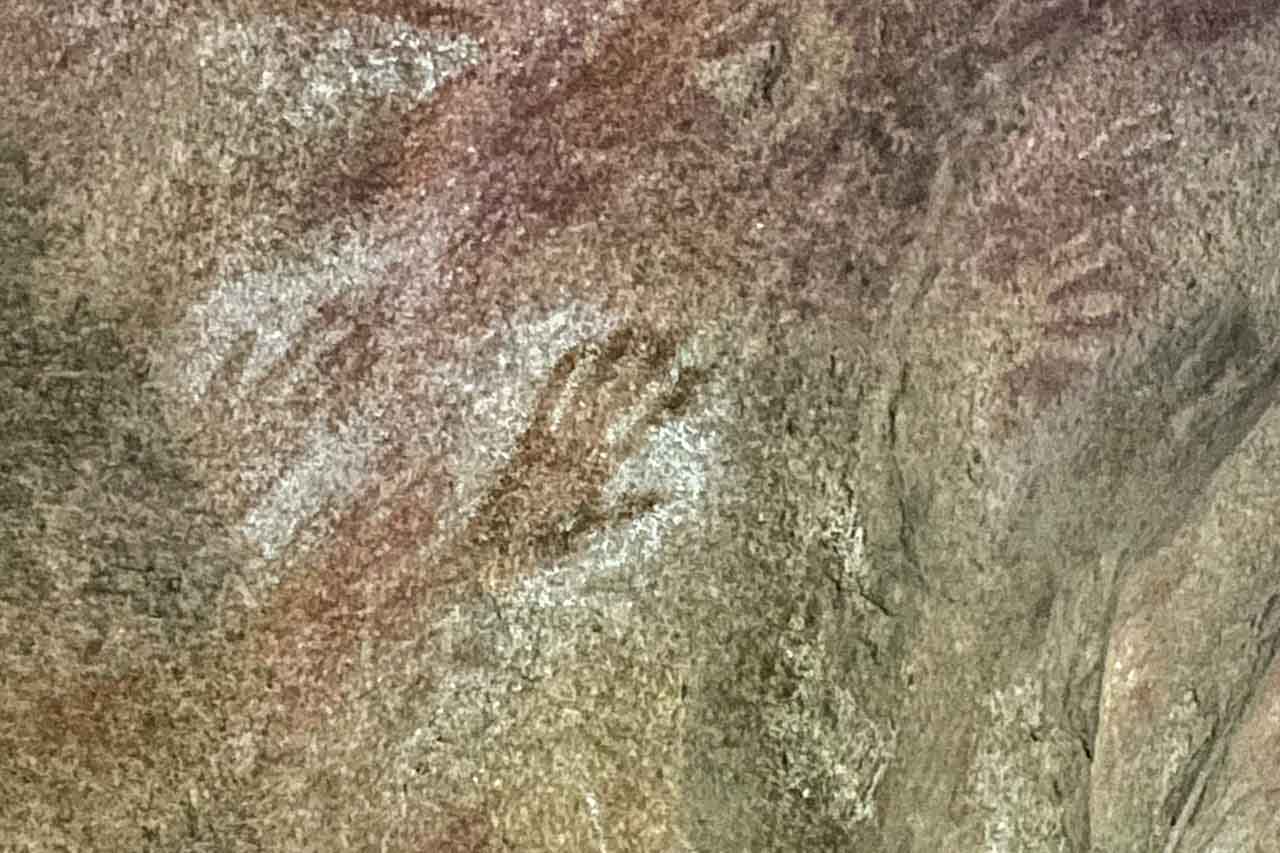 Several human handprints on a cave rock face