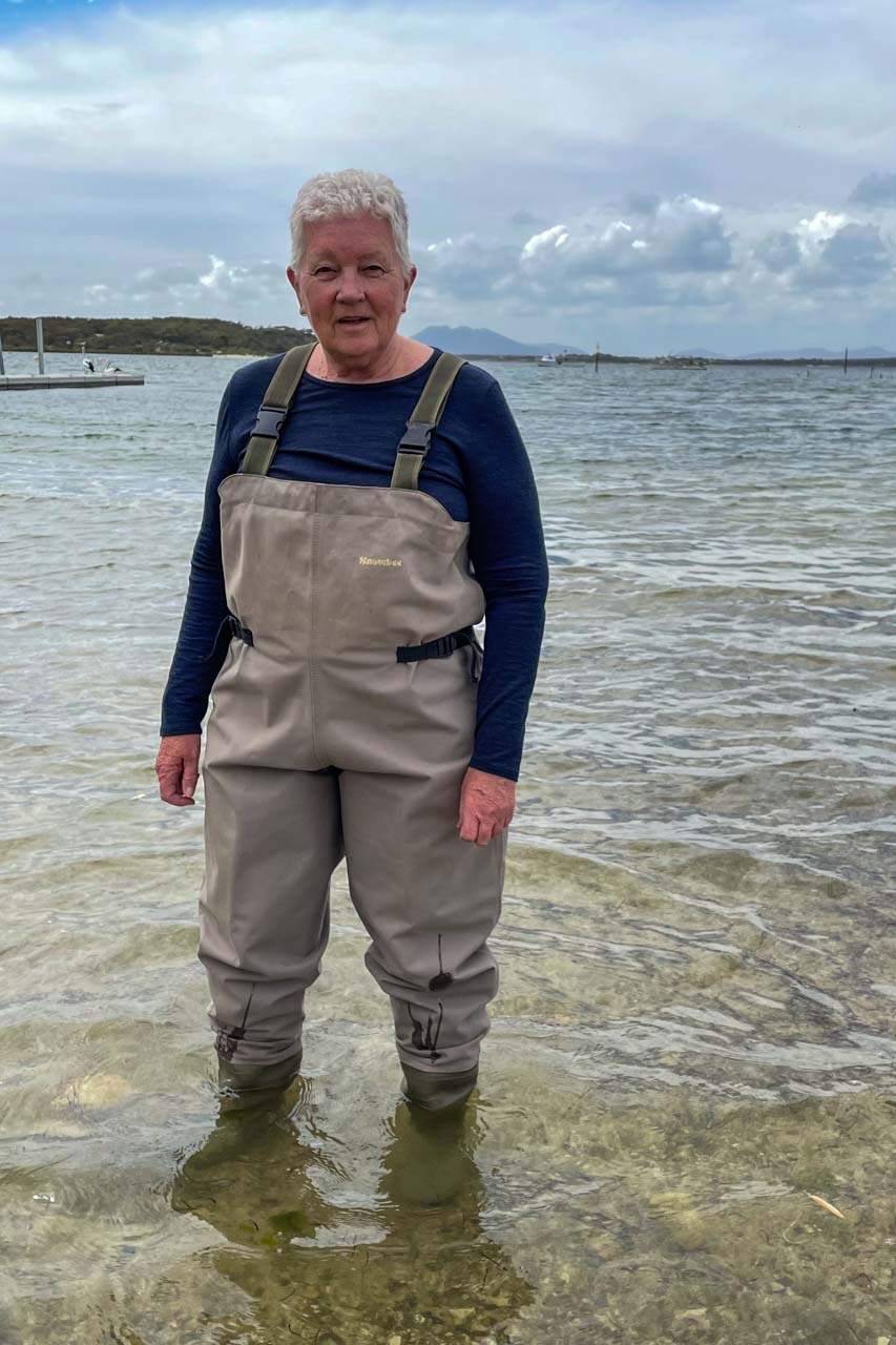 An image of a lady standing in shallow water dressed in wading pants and bib.