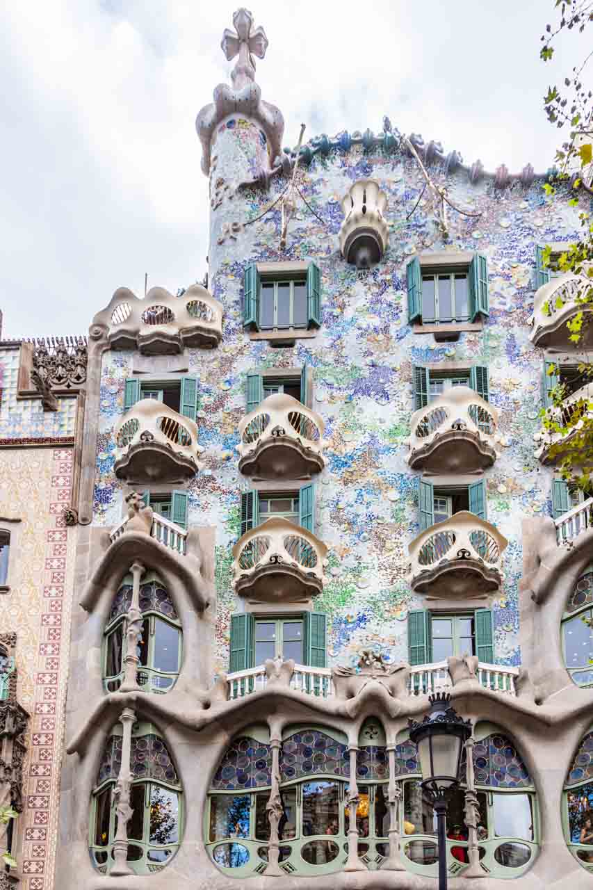 The facade of multistory house with triangle-shaped balconies and painted with flowers in pastel colours.