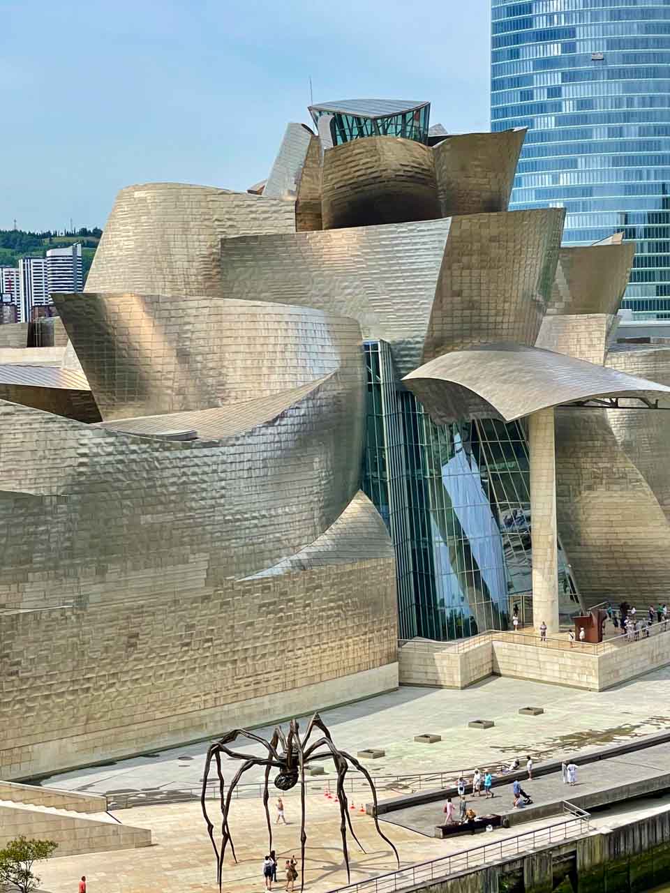 The Bilbao Guggenheim Museum forms a backdrop for a giant metal spider sculpture.