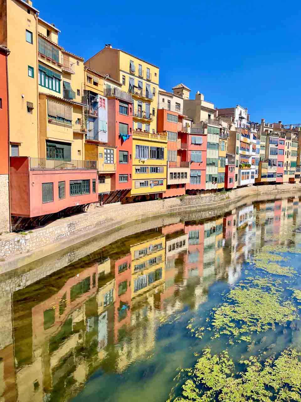 Multi-coloured houses line a river and are reflected in the waters of the river.