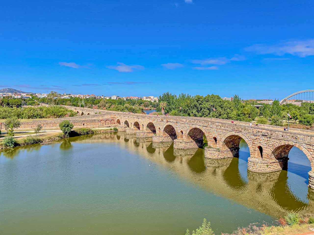 A stone arch bridge built by the ancient Romans is reflected in the river it spans.