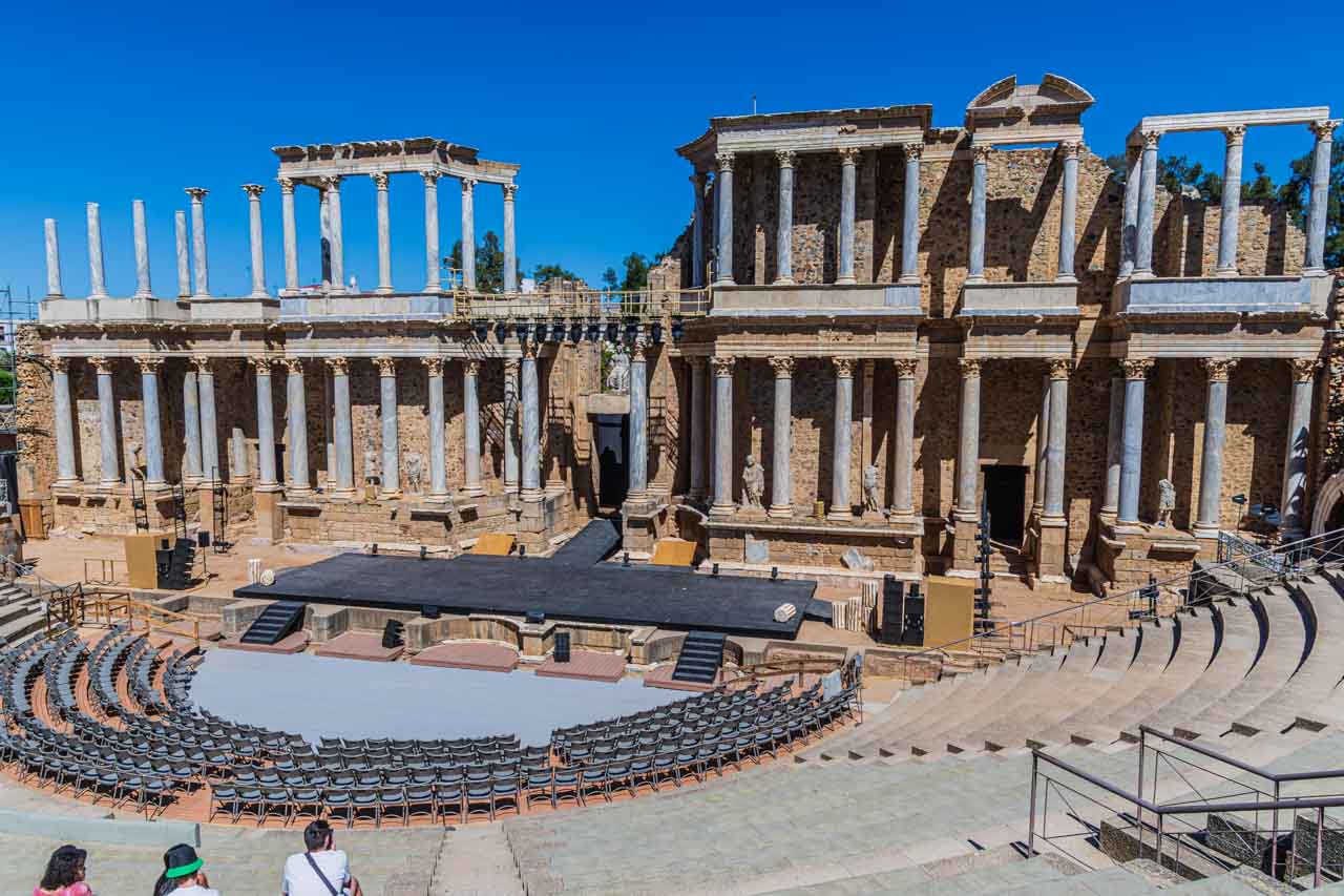The ruins of an ancient Roman theatre with stone and modern seating.