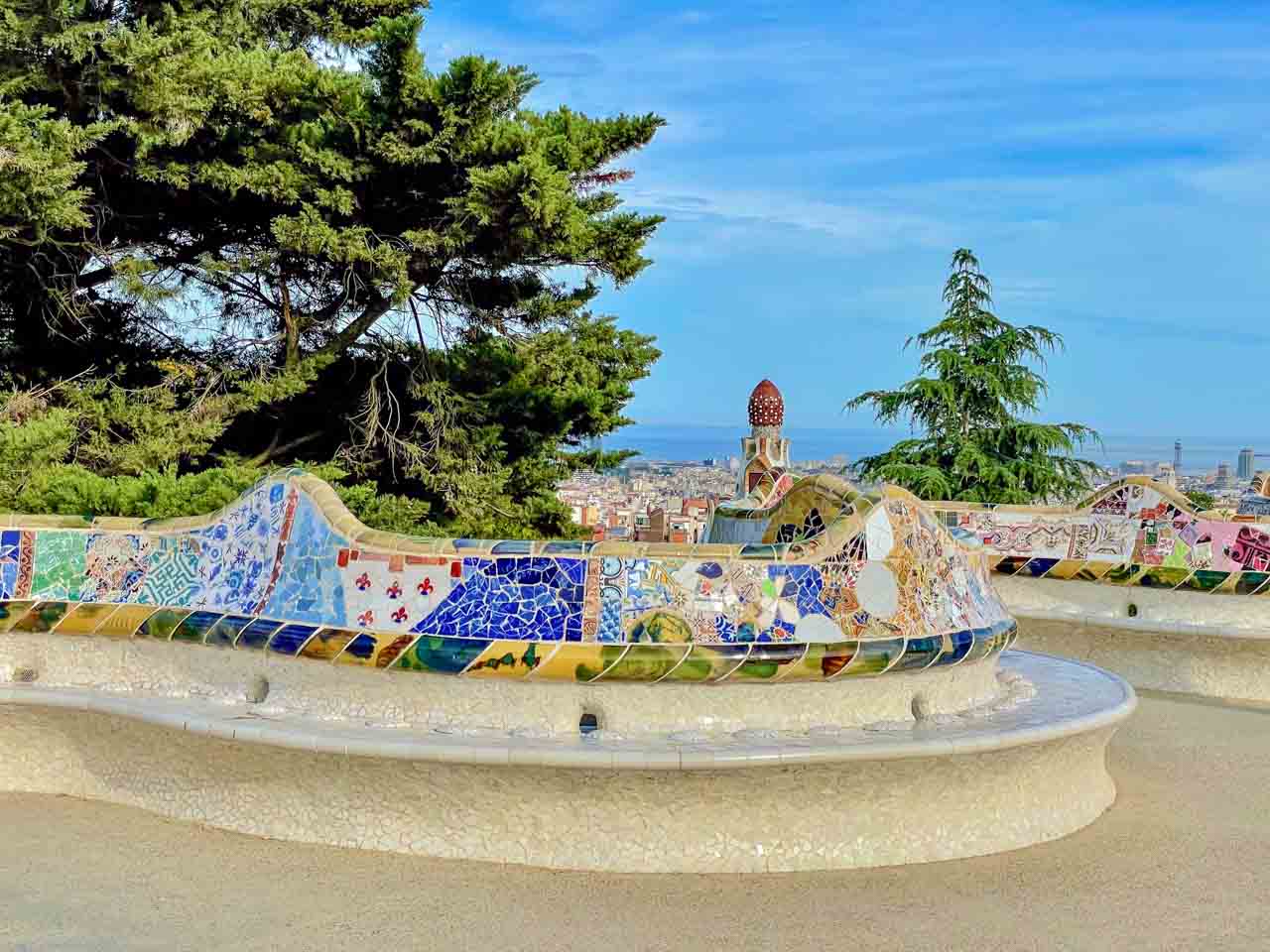 A winding snake-like bench covered in a mosaic of coloured broken tiles.