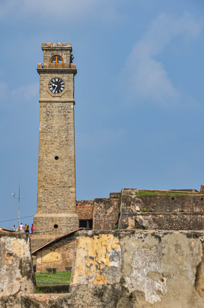 A stone clock tower is located on stone ramparts.