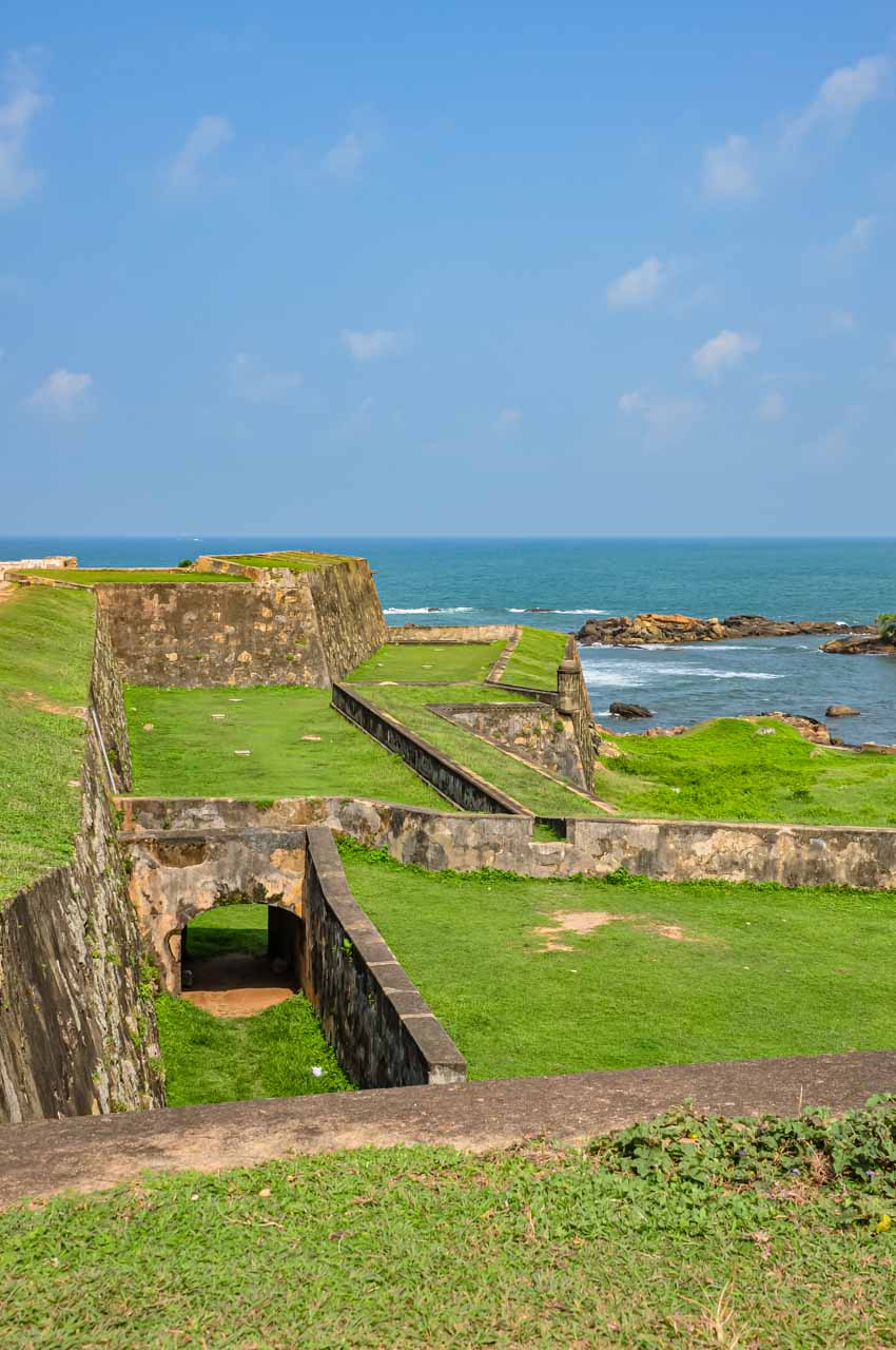 Stone ramparts covered with grass, with the ocean in the background.