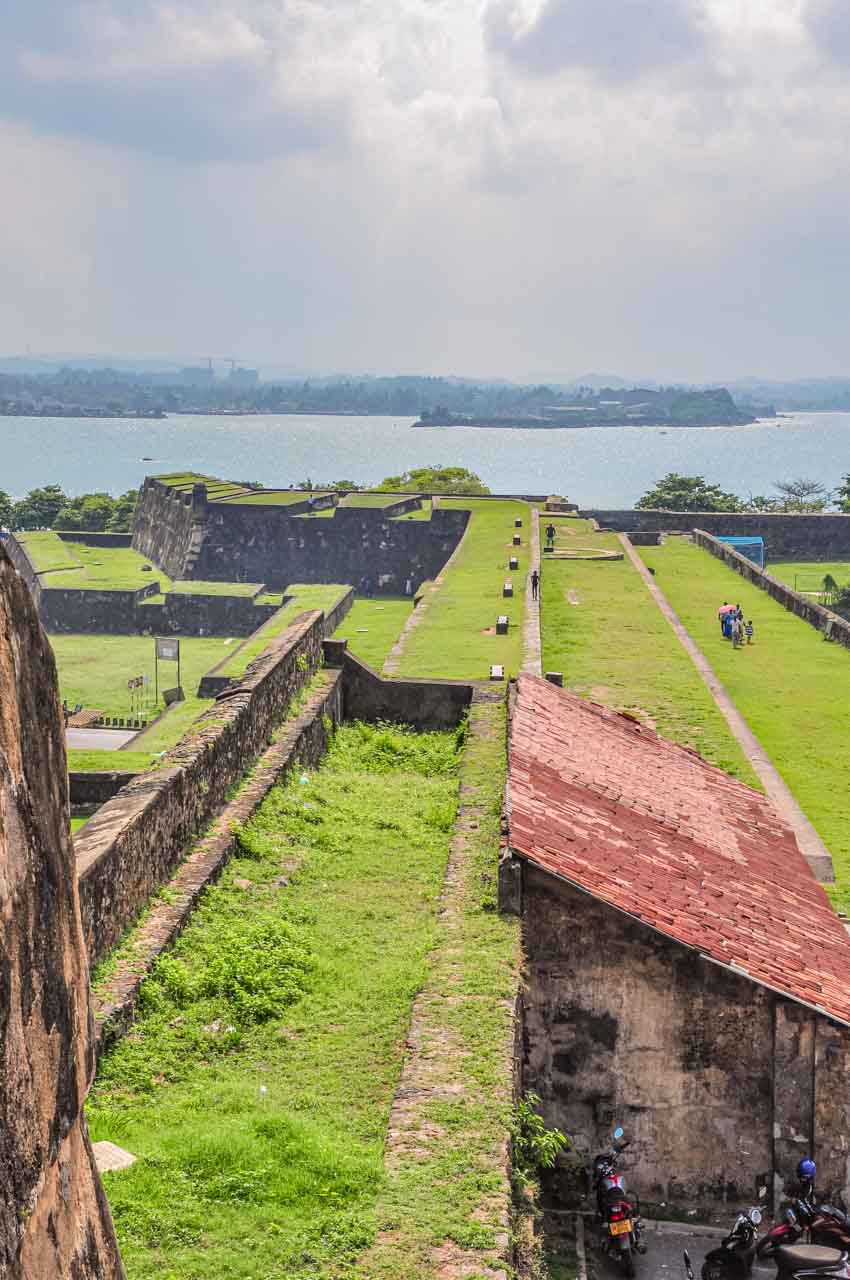 Stone ramparts covered in green grass with view to the harbour and town beyond.