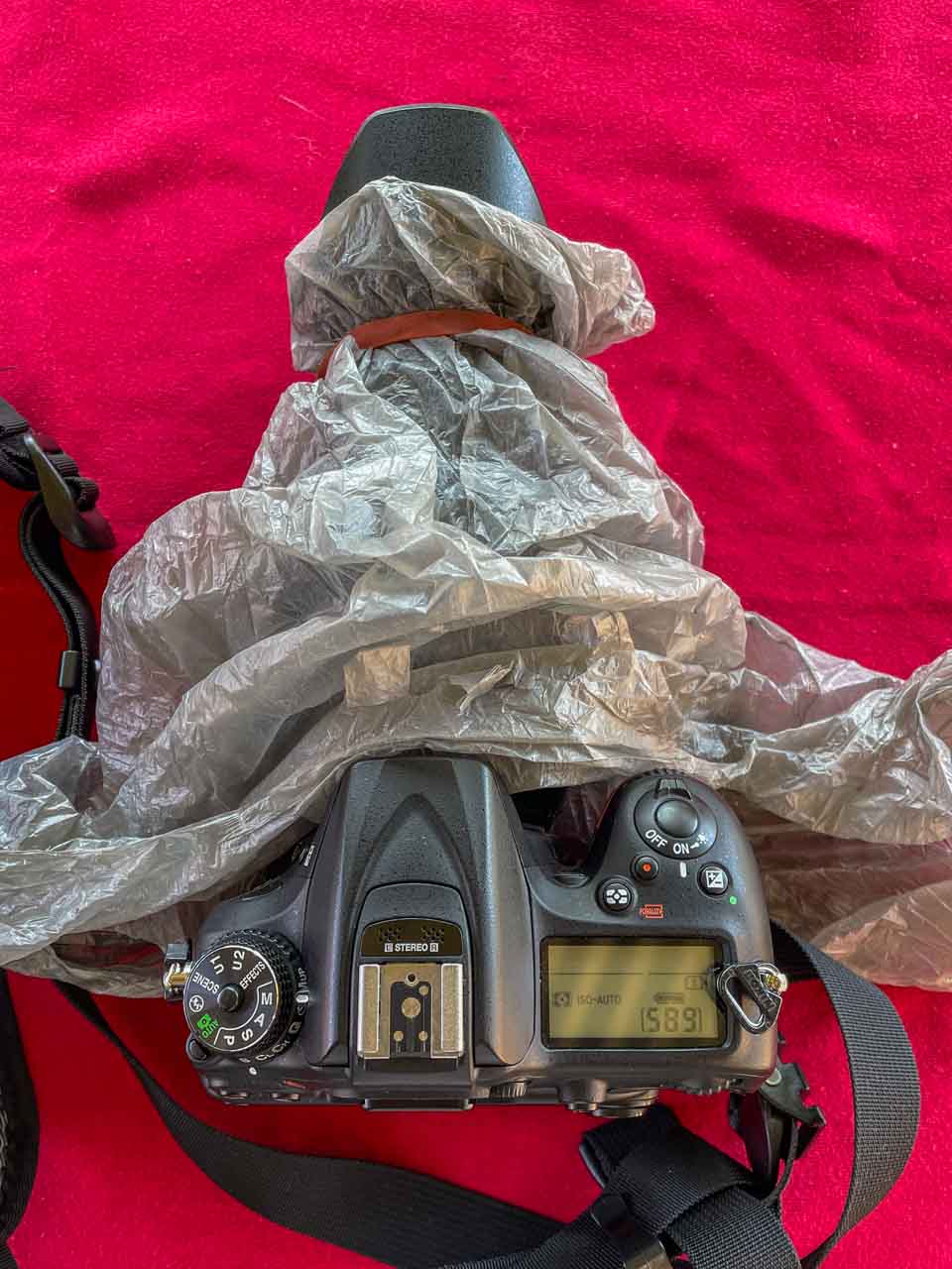 Top view of a DSLR camera with a plastic bag attached to the lens.